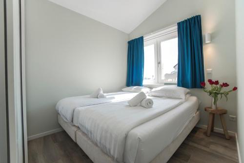 a bedroom with a large white bed with blue curtains at New Point in Zandvoort