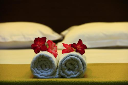 a pair of towels with red flowers on top of a bed at Nakula Guest House in Kuta