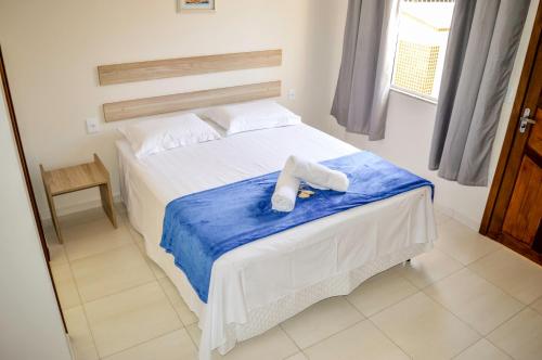 Una cama con un animal de peluche sentado encima. en Pousada Vila Regina, en Penha