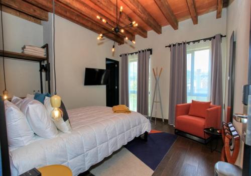 a bedroom with a white bed and a red chair at Antigua Trece Hotel Fusión in Guanajuato