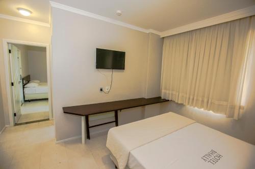 a bedroom with a bed and a desk with a television at Apart Hotel Bhally INN in Balneário Camboriú
