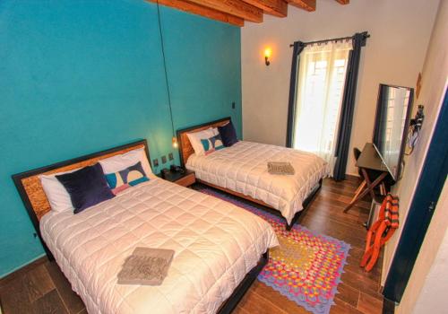 a bedroom with two beds and a blue wall at Antigua Trece Hotel Fusión in Guanajuato