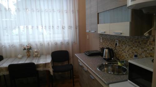 cocina con fregadero y barra con sillas en Apartments I & I, en Beregovo