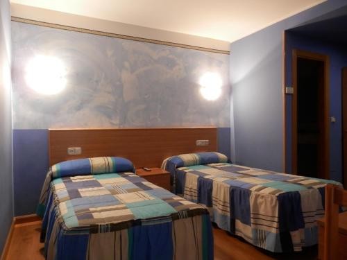 Habitación con 2 camas y una pintura en la pared. en Hotel Doña Maria en Gijón