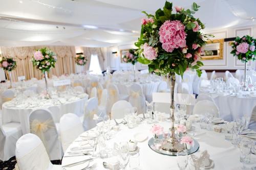 una sala de banquetes de boda con mesas blancas y flores rosas en The Original Rosslyn Inn, en Roslin