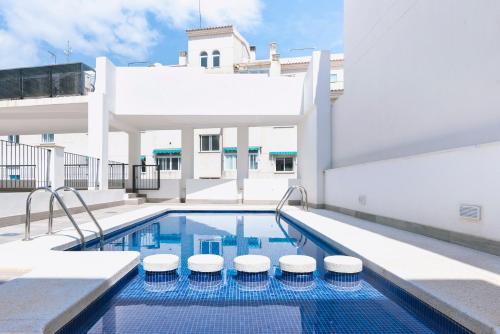 a swimming pool with stools next to a building at Casco Antiguo 1 Piscina, Terraza y Parking by Vero in Altea