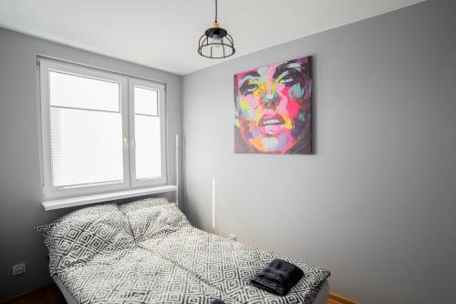 a bedroom with a bed and a painting on the wall at Apartament Dla Ciebie in Olsztyn