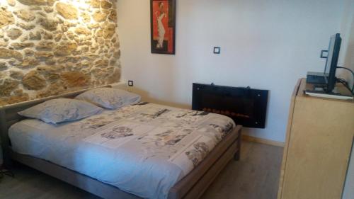 1 dormitorio con cama y pared de piedra en Le gite au tilleul en Vauhallan