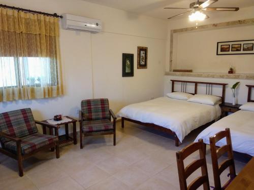 a bedroom with two beds and a table and chairs at Sunset Guest House in Kormakiti