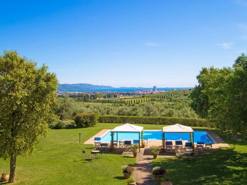 a garden with a swimming pool and umbrellas at Apartment Formula 1 by Interhome in Casa Fusi