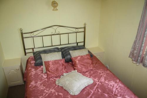 a bedroom with a bed with pink sheets and pillows at Guest House Kalnu pūpoli in Šengeida