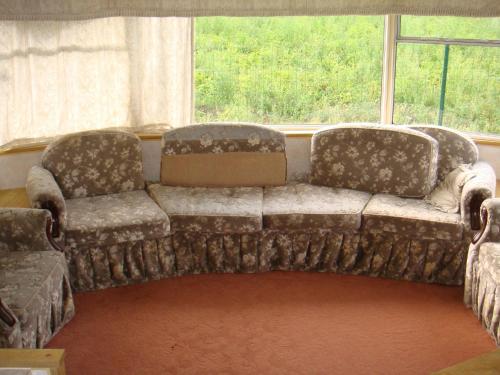 a couch and two chairs in a room with a window at Guest House Kalnu pūpoli in Šengeida