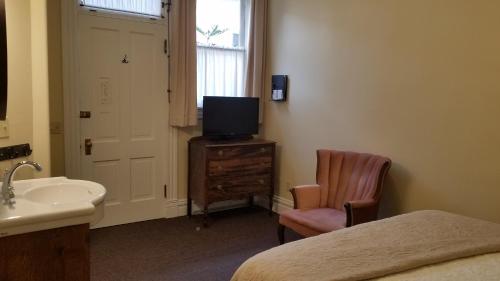 a bedroom with a bed and a sink and a television at Hotel Ouray - for 12 years old and over in Ouray