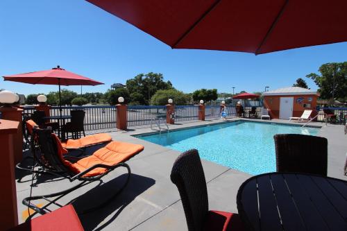 a swimming pool with chairs and an umbrella next to a swimming pool at Hotel Pensacola in Pensacola