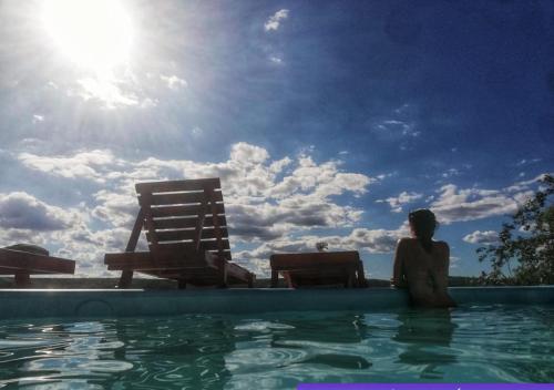 a woman sitting in the water in a swimming pool at Cabañas Club del Lago in La Falda