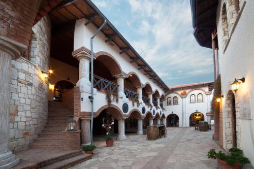a large building with a courtyard with stairs and tables at VINIFERA VINEYARDS HOTEL in Selcuk