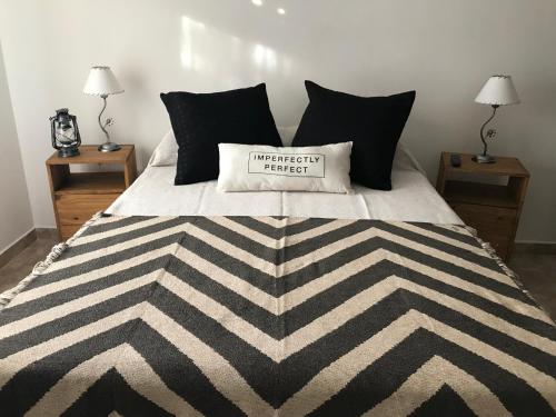 a bed with a black and white comforter with a pillow on it at Departamento Sofia in Tandil