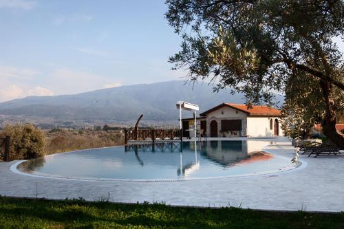 a swimming pool with a house and mountains in the background at VINIFERA VINEYARDS HOTEL in Selcuk