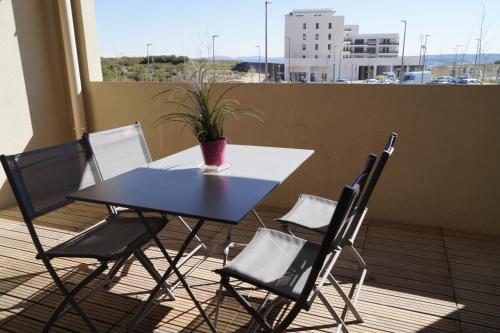 une table et des chaises sur un balcon avec une plante en pot dans l'établissement Cittazen Aix-en-Provence - Entre gare TGV et centre ville, calme et confort moderne, à Aix-en-Provence