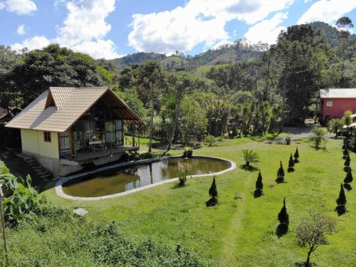 uma casa num campo com um lago e árvores em Pousada Silvestre em Visconde de Mauá
