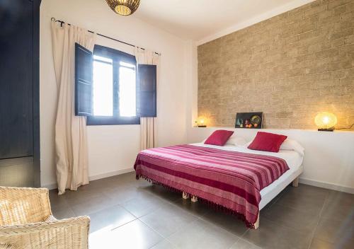 1 dormitorio con 1 cama con manta roja y ventana en Cortijo La Tenada Cabo de Gata en Los Albaricoques