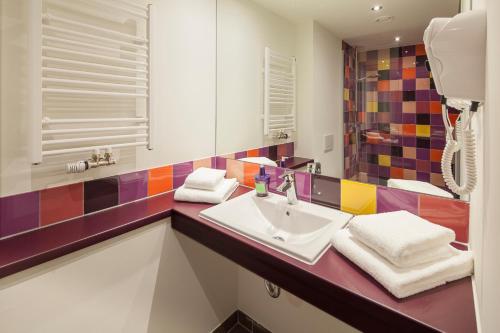 ein Bad mit einem Waschbecken und einem Spiegel in der Unterkunft Explorer Hotel Neuschwanstein in Nesselwang