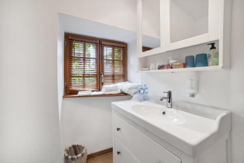 biała łazienka z umywalką i oknem w obiekcie Gîtes Saint Aubin w mieście Erquy