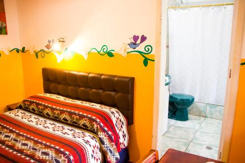 a room with a bed with a yellow wall at Hostal Riviera Sucre in Otavalo
