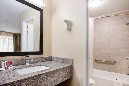 a bathroom with a sink and a mirror and a tub at Baymont by Wyndham Lake City in Lake City