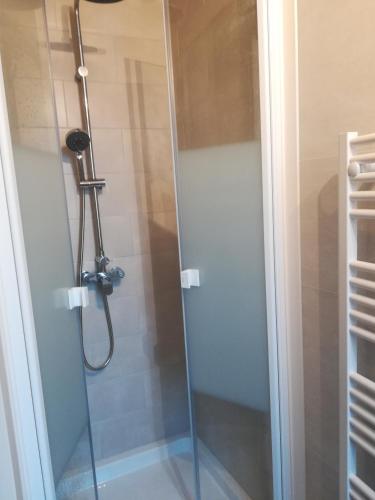 une douche dans une salle de bain avec une porte vitrée dans l'établissement Les Néréides, à Mers-les-Bains