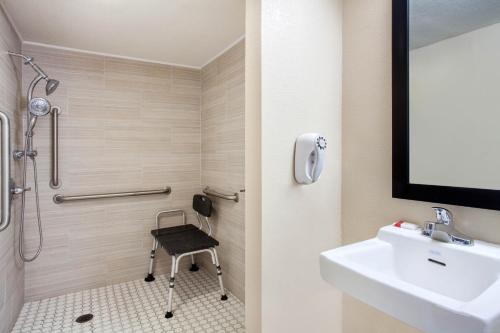 a bathroom with a shower and a sink and a chair at Baymont by Wyndham Lake City in Lake City