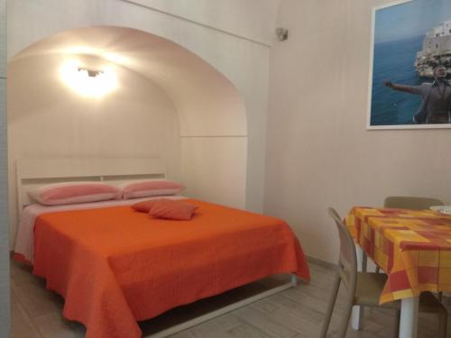 a bedroom with an orange bed and a table at GIUAMAR casa vacanza in Polignano a Mare