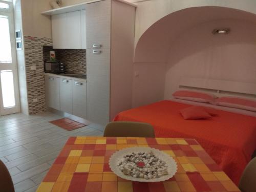 a bedroom with a bed and a table and a kitchen at GIUAMAR casa vacanza in Polignano a Mare