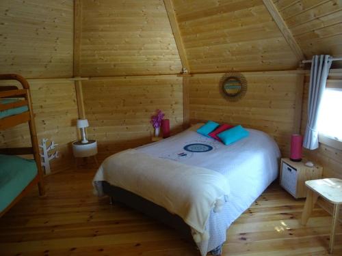 a bedroom with a bed in a log cabin at LES GITES DU PARC KOTA DOUBLE climatisé in Mantoche