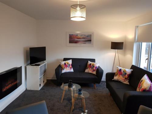 a living room with a couch and a tv at Carnegie Place in East Kilbride