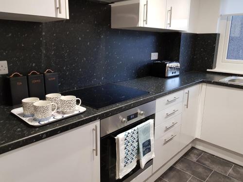 a kitchen with white cabinets and black counter tops at Carnegie Place in East Kilbride