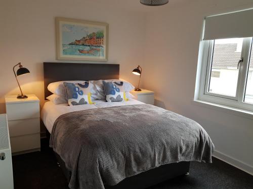 a bedroom with a bed with two lamps and a window at Carnegie Place in East Kilbride