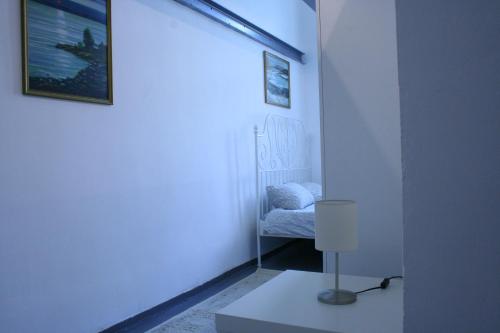 ein weißes Zimmer mit einem Bett und einer Lampe in der Unterkunft Sleepover City Center GuestRooms in Budapest
