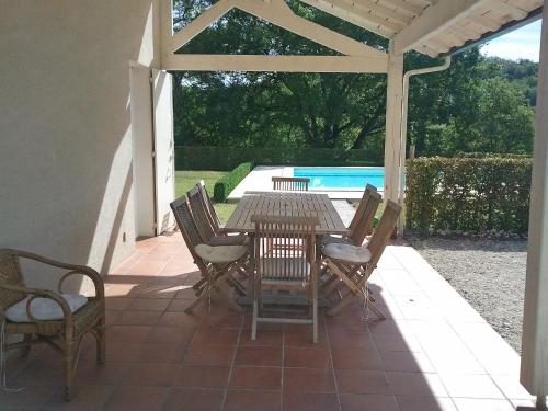 patio ze stołem i krzesłami oraz basenem w obiekcie Holiday Home Lapeyriere by Interhome w mieście Saint-Pantaléon
