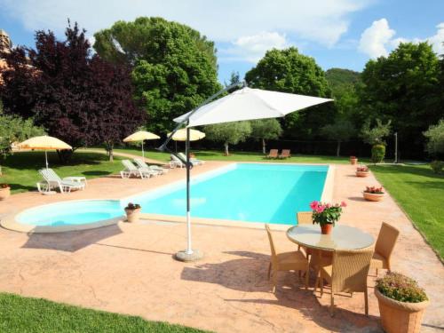 a swimming pool with a table and an umbrella at Villa Paolotti by Interhome in Bettona