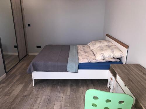 a small bedroom with a bed and a green chair at Goleniow Apartment in Gollnow