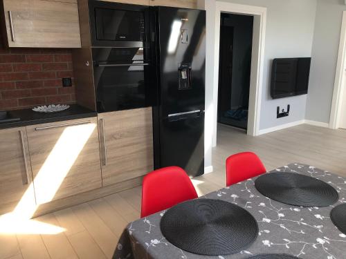 a kitchen with a black refrigerator and a table with red chairs at Goleniow Apartment in Gollnow