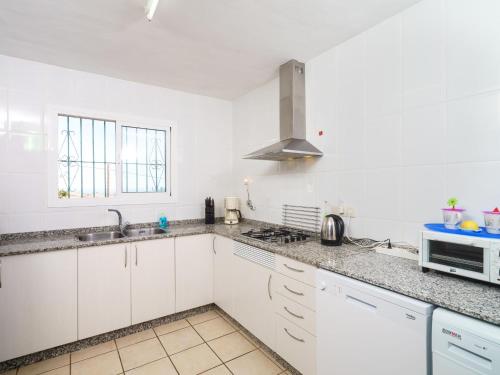 a white kitchen with a sink and a microwave at Holiday Home La Caissa by Interhome in Benitachell