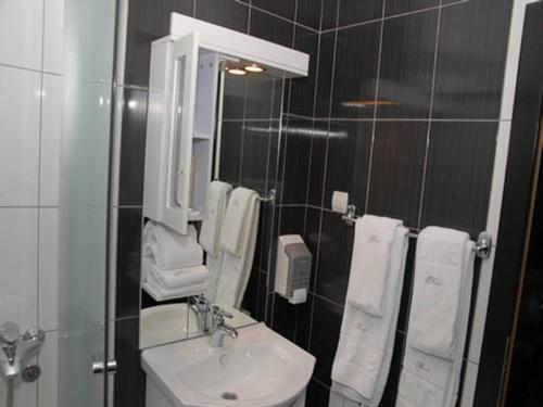 La salle de bains est pourvue d'un lavabo, d'un miroir et de serviettes. dans l'établissement Hotel Novak, à Zvornik