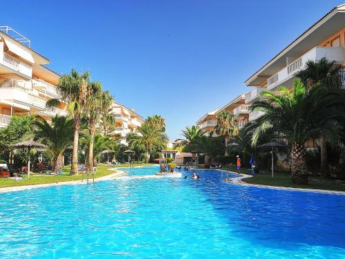 a large swimming pool with palm trees in a resort at Apartment Nou Fontana-4 by Interhome in Jávea