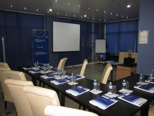 a conference room with a table and chairs and a screen at Hotel Novak in Zvornik