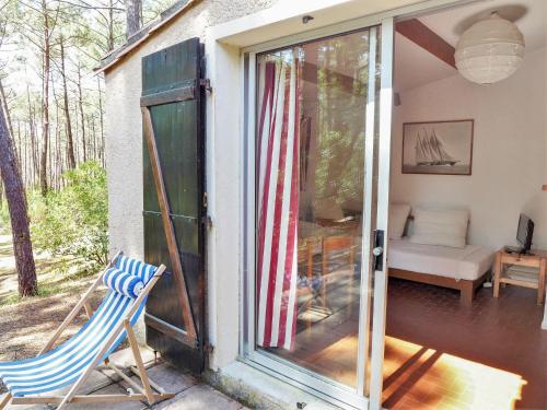 una puerta corredera de cristal abierta de una casa con silla en Holiday Home Les Palombes-3 by Interhome, en Lacanau-Océan