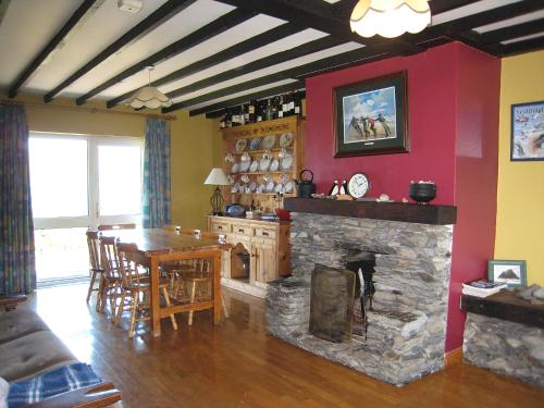 a living room with a stone fireplace and a dining room at Holiday Home Seaside Cottages-2 in Valentia Island