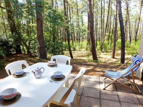a white table and chairs on a patio with trees at Holiday Home Les Palombes-3 by Interhome in Lacanau-Océan