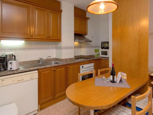 una cocina con armarios de madera y una mesa de madera con una botella de vino en Apartment Primer de Maig by Interhome, en Sitges